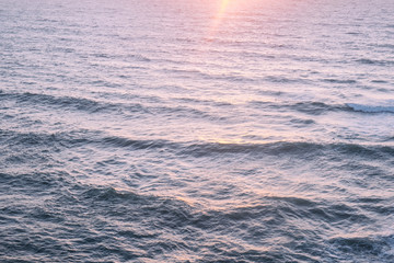 Aerial view over the ocean of sun rising over water waves surface