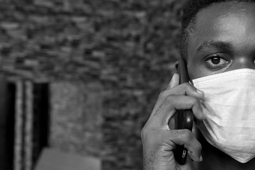 young black man wearing a face mask making a phone call close up