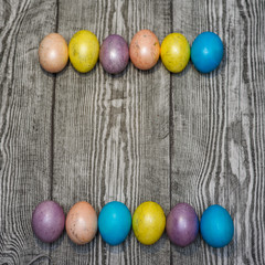 Many multi colored easter eggs on the wooden background.