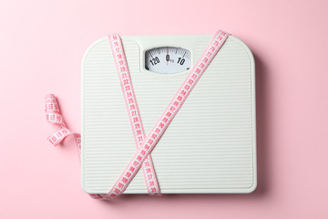 Scales and measuring tape on pink background. Weight loss concept