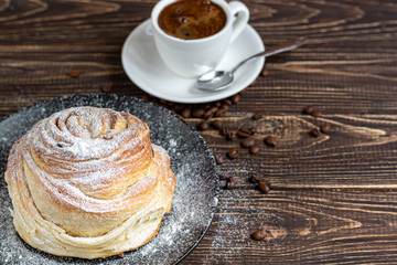 Bakery products with raisins and dried fruits are located on a dark wooden background. Sprinkled with icing sugar. Kraffins. Easter food.