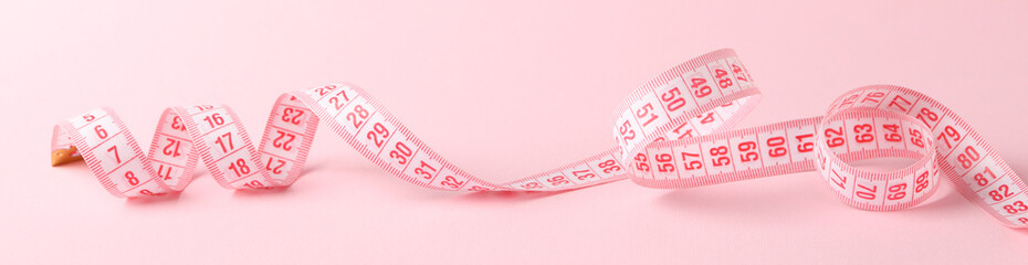 Measuring tape on pink background. Weight loss concept