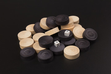 Obraz na płótnie Canvas Backgammon. Board game. White dice and white and black chips for playing on a black background. Game for recreation
