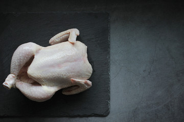 Fresh chicken without spices on dark background, selective focus. Healthy food, diet or cooking concept. Top view, copy space.