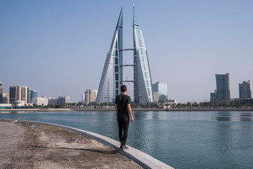young male traveler walking towards skyscraper in manama bahrain