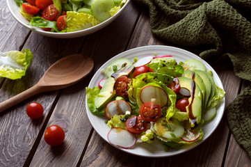 Fresh spring salad with lettuce, cucumber, cherry tomatoes, radishes, spring onion and avocado topped with balsamic glaze and extra virgin olive oil.