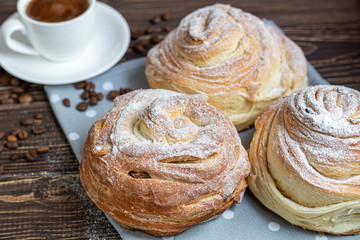 Bakery products with raisins and dried fruits are located on a dark wooden background. Sprinkled with icing sugar. Kraffins. Easter food.