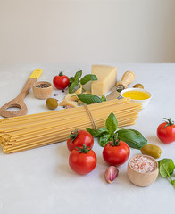 Italian pasta ingredients for cooking spaghetti on a white table.