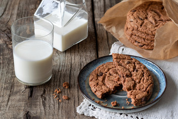 Milk and chocolate american cookies on a wooden table.