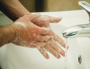 male hands in soap under the tap with water