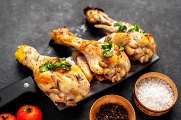grilled chicken legs with spices on a knife on a stone background