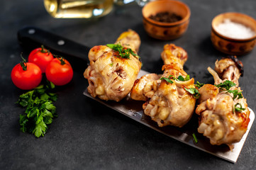 grilled chicken legs with spices on a knife on a stone background