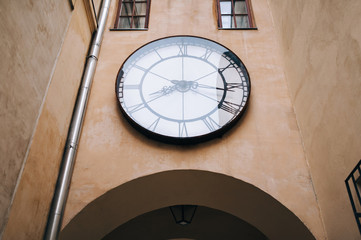 Fototapeta na wymiar An old vintage clock under glass hangs over an arch inside the Armenian courtyard in Lviv (Ukraine).