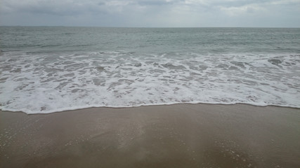 Fototapeta na wymiar sea ??horizon, waves with foam run onto yellow sand