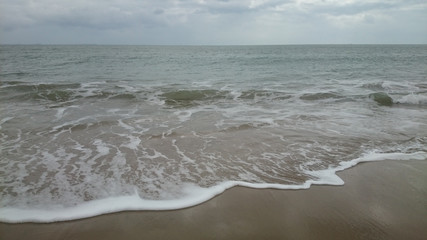 sea ??horizon, waves with foam run onto yellow sand