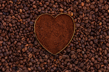 Ground fresh coffee in the shape of a heart on coffee beans background
