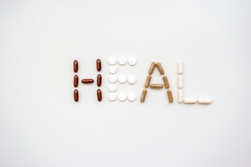 The word heal spelled out from different types of medical pills and capsules set of bright white background