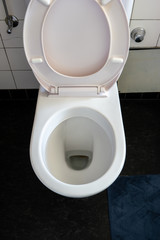 Clean toilet bowl with the seat up in a small bathroom