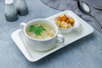 Chicken soup bouillon in a plate on grey table