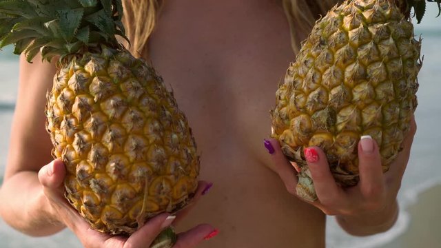 A woman covers her chest with pineapples