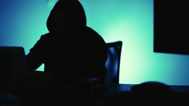 A computer programmer or hacker prints a code on a laptop keyboard to break into a secret organization system.