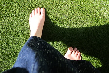 庭の人工芝の上をはだしで歩く女性の足元