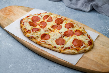 Pepperoni pizza on Roman dough pinsa on grey table