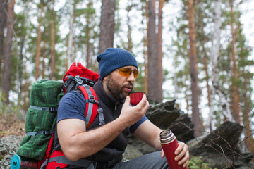 Fototapeta premium Male tourist drinks tea in the rocky forest.