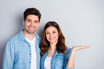 Photo attractive lady handsome guy hugging hold open arm empty space demonstrating novelty product good mood wear casual denim shirts isolated grey color background