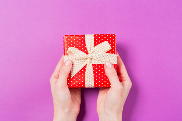 Close-up of woman hands holding gift present box on purple background. Holiday Valentine's Day Mother's Day Wedding concept. Free space. Copy space. 