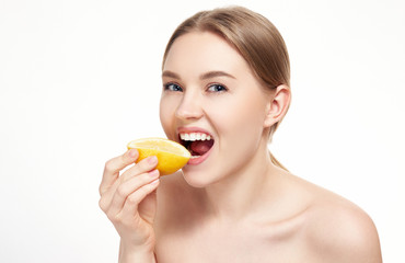 Young attractive girl posing at studio with lemon. Beautiful female face with healthy skin and eyes. Young blonde natural woman with vivid makeup. Skin care