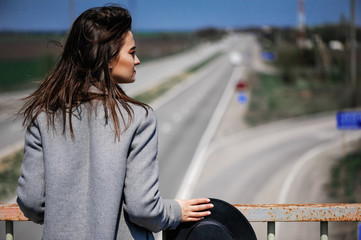 Fashionable attractive young girl posing on the road. Woman thought about life ways