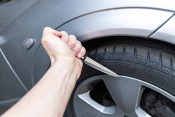 Vorhabe in Autoreifen zu stechen mit scharfen Messer