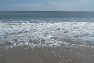 sea ??horizon, waves with foam run onto yellow sand