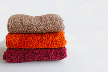 red, orange and brown towels in a stack on a white background