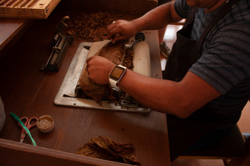 Economic process for rolling tobacco using a hand-held rolling machine a worker in Mexico