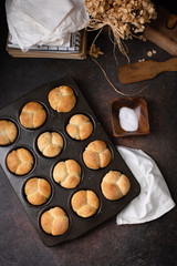 Fototapeta na wymiar Freshly Baked Homemade Cloverleaf Rolls in Muffin Tin: Rustic, Dark Background