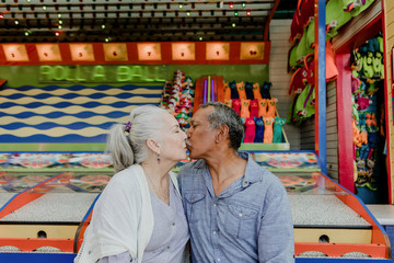 Obraz premium Happy senior couple kissing in a theme park