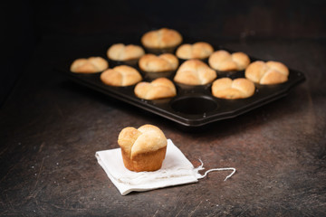 Freshly Baked Homemade Cloverleaf Rolls in Muffin Tin: One Roll on Napkin in Front; Rustic, Dark...