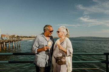 Happy couple enjoying ice cream by the sea