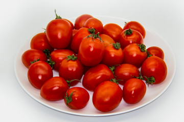 Ripe fresh red cherry tomatoes on a white plate against white background.  Beautiful and healthy fresh cherry tomatoes without GMO.