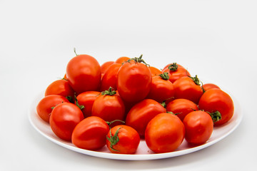 Ripe fresh red cherry tomatoes on a white plate against white background.  Beautiful and healthy fresh cherry tomatoes without GMO.