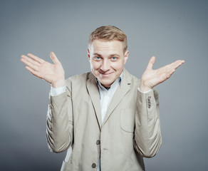 Closeup portrait of angry, annoyed unhappy young man, arms out asking what's the problem who cares so what, I don't know. Isolated on gray background.