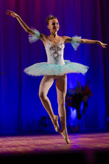 Young girl ballerina in a light blue dress tutu dancing performance of a ballet on stage in a theater © Kozlik_mozlik
