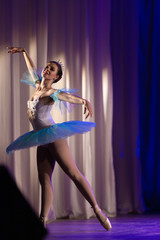 Young girl ballerina in a light blue dress tutu dancing performance of a ballet on stage in a theater © Kozlik_mozlik