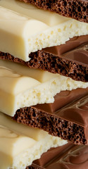 broken pieces of textured porous chocolate, white and milk, closeup background