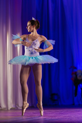 Young girl ballerina in a light blue dress tutu dancing performance of a ballet on stage in a theater © Kozlik_mozlik