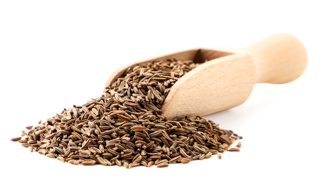 Cumin seeds in a wooden spoon on a white background. Isolated