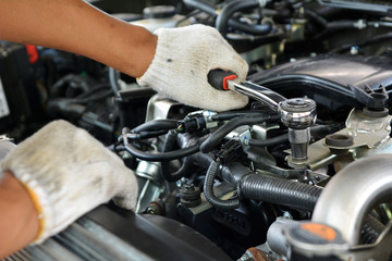 Fototapeta premium Automotive mechanic working in a garage. Repair service. Mechanic working on a diesel engine, close up. Technician hands of car mechanic in doing auto repair service and maintenance worker repairing.