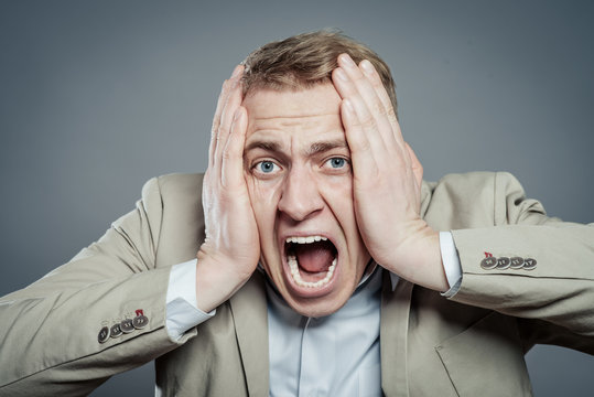 Young man screaming surprised looking at camera.